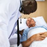 Médico urologista examinando seu paciente, um homem de por volta 70 anos, diagnosticado com adenocarcinoma de próstata.