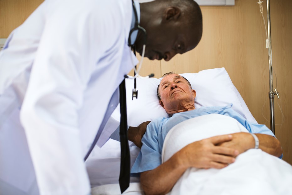 Médico urologista examinando seu paciente, um homem de por volta 70 anos, diagnosticado com adenocarcinoma de próstata. 