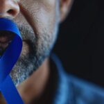 Homem mais velho segurando o símbolo do Novembro Azul em mãos para representar qual o tamanho da próstata em risco de câncer.
