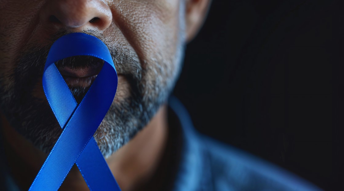 Homem mais velho segurando o símbolo do Novembro Azul em mãos para representar qual o tamanho da próstata em risco de câncer. 