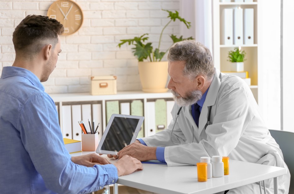 Médico urologista em seu consultório médico explicando para seu paciente sobre as funções da próstata.