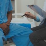 Homem com suspeita de próstata aumentada relatando sintomas ao médico em consulta.