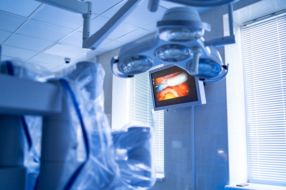 Ambiente cirúrgico moderno com monitor exibindo imagens internas, ilustrando tecnologias como laparoscopia e cirurgia robótica.