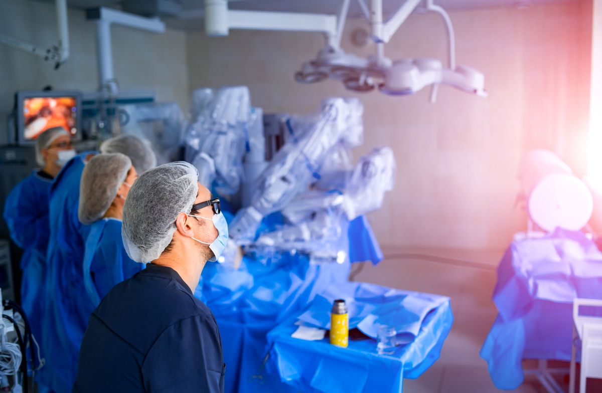 Centro cirúrgico moderno com cirurgia robótica em andamento, representando tecnologia e desafios do procedimento.