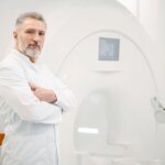 Médico em frente a equipamento que realiza exame pet scan para câncer.