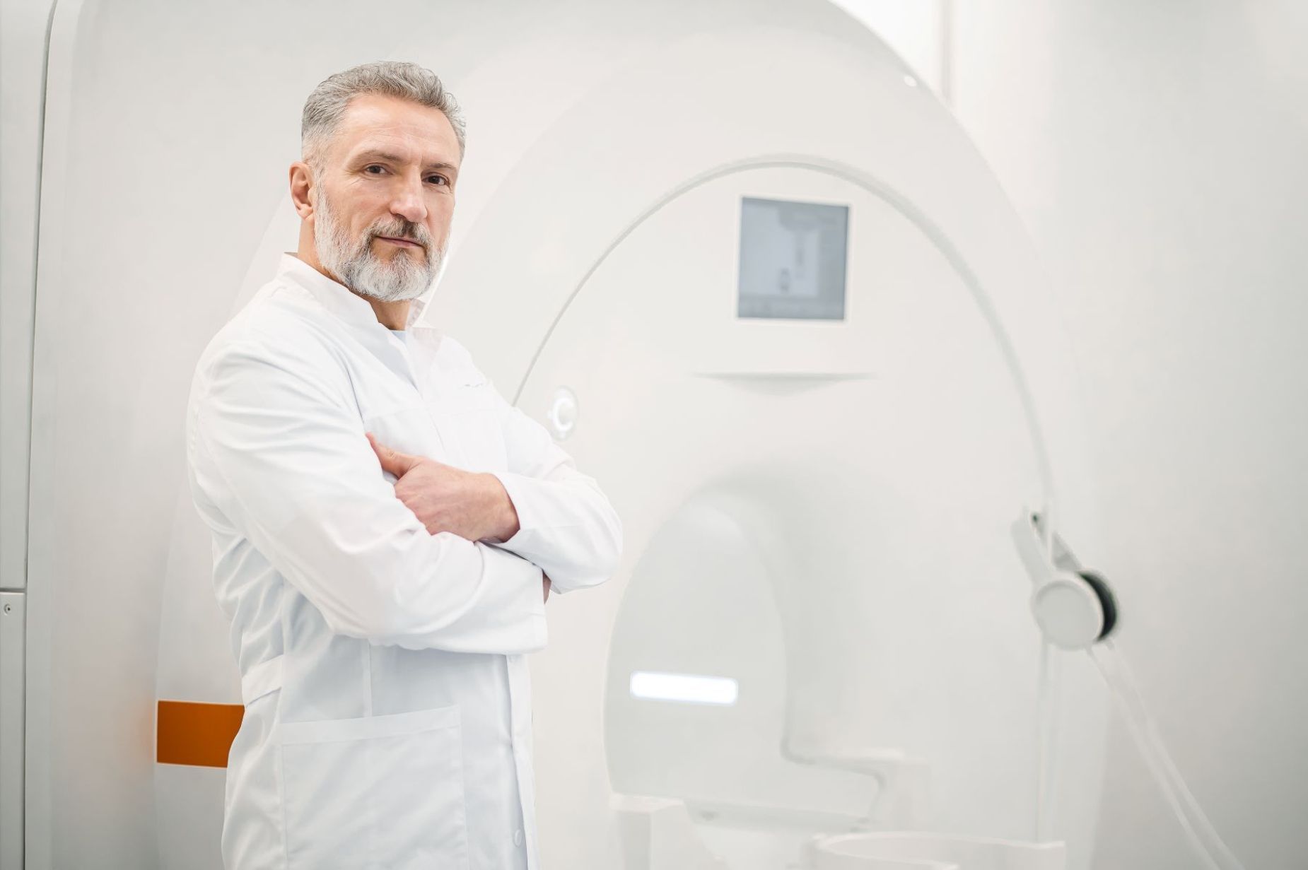 Médico em frente a equipamento que realiza exame pet scan para câncer.