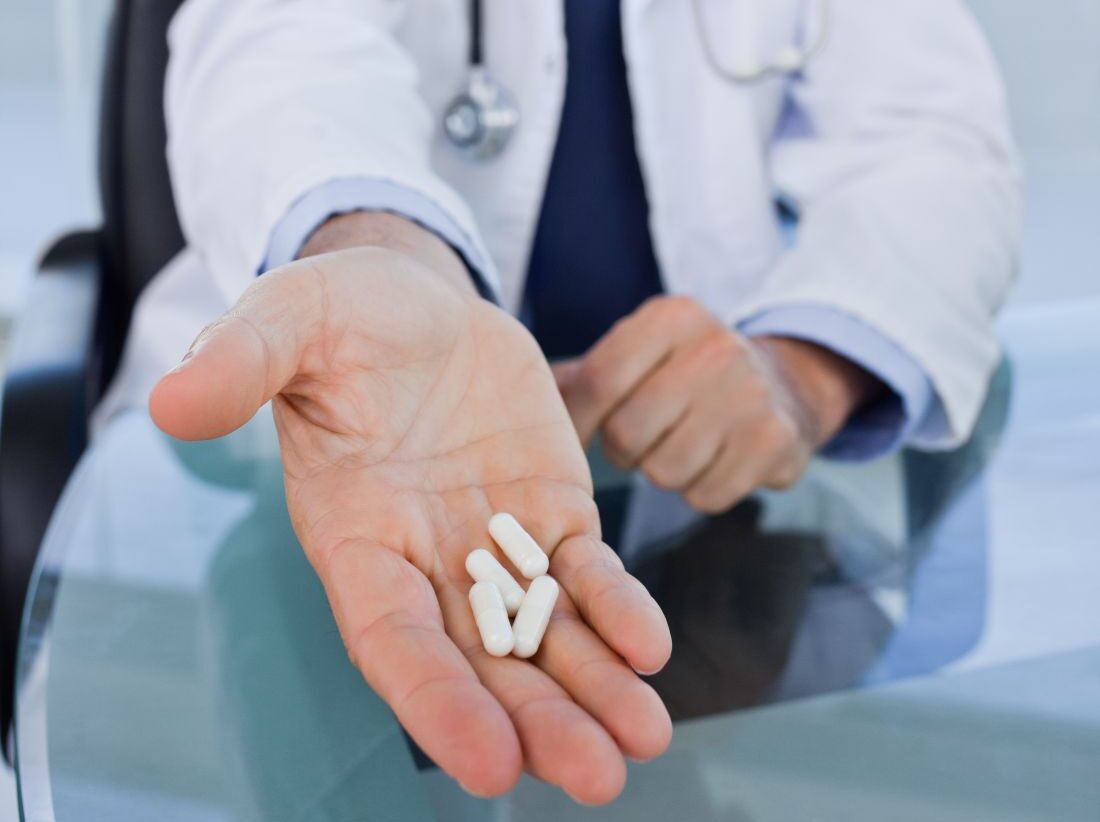 Médico urologista esticando mão com medicamentos que aumentam o PSA à sua frente.