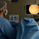 Cirurgião realiza HoLEP em centro moderno com laser de hólmio e monitores de alta definição, técnica minimamente invasiva.