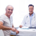 Paciente em consulta com urologista, discutindo vida sexual e retorno às relações após tratamento de câncer de próstata.