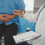 Médica atende paciente com desconforto pélvico, indicando exame ou tratamento para sintomas urinários e próstata aumentada.